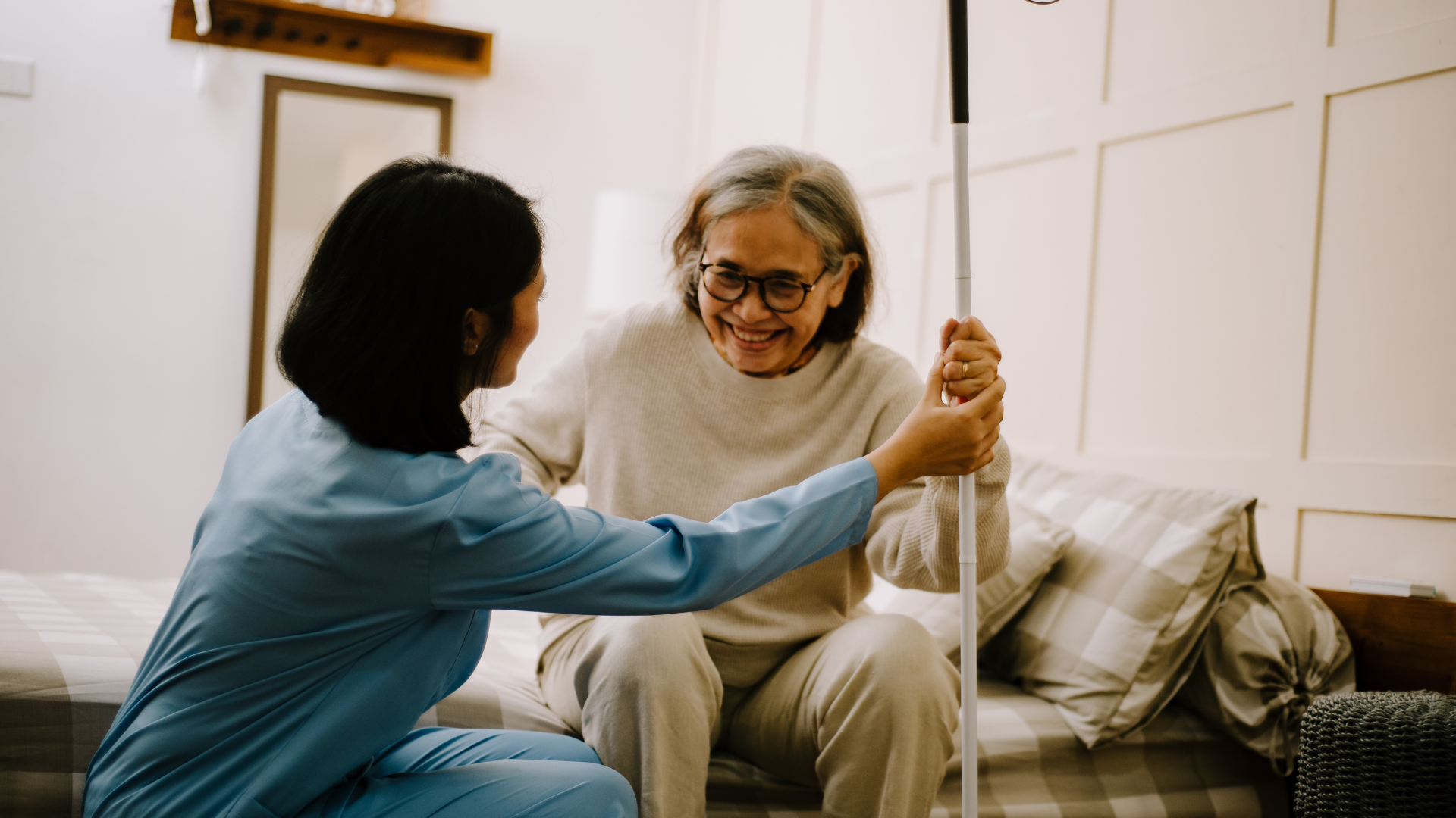 Aide au lever d’une personne âgée par une professionnelle, dans une chambre.