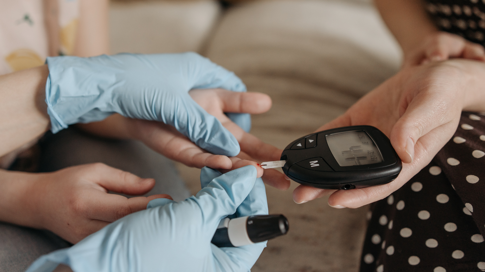 Mesure de la glycémie avec lecteur et bandelette par une infirmière gantée.